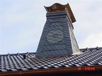 Dekorative Verkleidung eines Schornsteins auf einem Steildach mit Schiefer